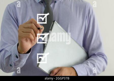 Geschäftsmann mit einem Stift mit einem Häkchen auf dem Quadrat auf einem virtuellen Bildschirm Stockfoto