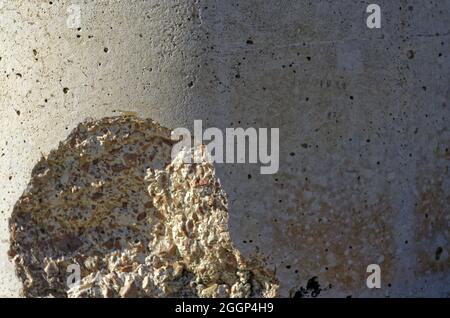 Nahaufnahme einer schmutzigen grungen alten rostigen weißen Wand mit zertrümmerten Teil unter Sonnenlicht Stockfoto