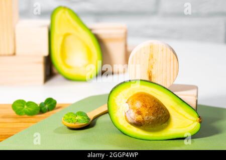 Hälften von reifen Avocado und Micro Green auf Holzbrett serviert auf dem Tisch, weißer Hintergrund, gesunde ölige Lebensmittel, Keto-Diät, Nahaufnahme. Stockfoto