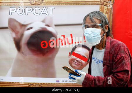 Bangkok, Thailand. September 2021. Ein Mann mit Gesichtsmaske kommt während der Demonstration an einem Plakat mit einem Foto einer PopCat und Thailands Premierminister Prayuth Chan O-Cha vorbei. Demonstranten fordern, dass Thailands Premierminister Prayut Chan-o-cha zurücktritt und die Regierung für ihr grobes Missmanagement der Covid-19-Pandemie zur Verantwortung gezogen wird. (Foto von Chaiwat Subprasom/SOPA Images/Sipa USA) Quelle: SIPA USA/Alamy Live News Stockfoto