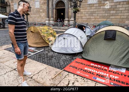 Barcelona, Spanien. September 2021. Ein Passant liest ein Banner vor dem Zeltlager, das während eines Streiks auf der Plaza de Sant Jaume aufgestellt wurde.am zweiten Tag des Hungerstreiks auf der Plaza Sant Jaume von Geschäftsleuten und Ausgeharbeitern nach dem TSJC (Supreme Court of Justice of Catalonia) Bestätigte die Argumente der Generalitat de Catalunya, das Nachtleben wegen der sogenannten fünften Welle von Covid19 geschlossen zu halten. Kredit: SOPA Images Limited/Alamy Live Nachrichten Stockfoto