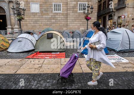 Barcelona, Spanien. September 2021. Eine Frau mit einem Einkaufswagen kommt an einem Zeltlager vorbei, das während eines Streiks auf der Plaza de Sant Jaume eingerichtet wurde.Zweiter Tag des Hungerstreiks auf der Plaza Sant Jaume durch Geschäftsleute und Nachtlebender nach dem TSJC (Supreme Court of Justice of Catalonia) Bestätigte die Argumente der Generalitat de Catalunya, das Nachtleben wegen der sogenannten fünften Welle von Covid19 geschlossen zu halten. Kredit: SOPA Images Limited/Alamy Live Nachrichten Stockfoto