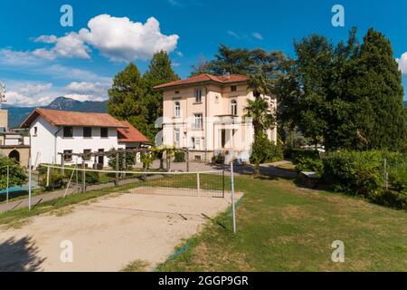 Große und alte Villa mit großem Garten um sie an einem sonnigen Sommertag, Beachvolleyballplatz Stockfoto