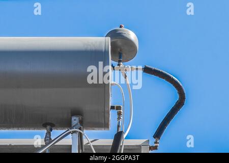 Wasserkocher Heizung Tank-System und heiße Technologie auf dem Dach des Hauses gegen den blauen Himmel. Stockfoto