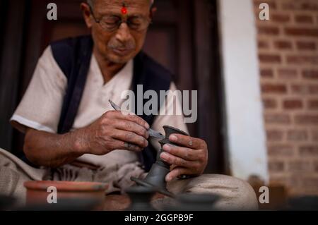 (210902) -- BHAKTAPUR, 2. September 2021 (Xinhua) -- Ein Handwerker arbeitet am 1. September 2021 an einer Töpferei auf einem Töpferplatz in Bhaktapur, Nepal. Bhaktapur ist bekannt für seine jahrhundertealte Töpferei, die über Generationen weitergegeben wurde. Die in Bhaktapur hergestellte Keramik wird aufgrund der Verwendung von schwarzem Ton, der nur an einem Ort gefunden werden kann und nur einmal im Jahr von den Bhaktapur-Ureinwohnern gegraben werden kann, als überlegen angesehen. (Xinhua/Sulav Shrestha) Stockfoto