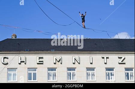 02. September 2021, Sachsen, Chemnitz: Peter Bessler balanciert auf dem Theaterplatz in Chemnitz in einer Höhe von etwa 20 Metern über eine Slackline. Slackline-Künstler werben mit dieser Aktion für das 15. Slackfest, das vom 3. Bis 5. September in Chemnitz stattfindet. Foto: Hendrik Schmidt/dpa-Zentralbild/dpa Stockfoto