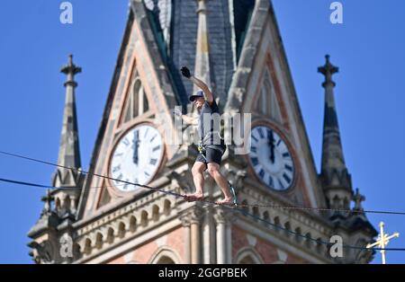 02. September 2021, Sachsen, Chemnitz: Peter Bessler balanciert vor der Peterskirche auf dem Theaterplatz in Chemnitz auf rund 20 Metern Höhe über einer Slackline. Slackline-Künstler werben mit dieser Aktion für das 15. Slackfest, das vom 3. Bis 5. September in Chemnitz stattfindet. Foto: Hendrik Schmidt/dpa-Zentralbild/dpa Stockfoto