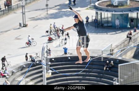 02. September 2021, Sachsen, Chemnitz: Peter Bessler balanciert über dem Theaterplatz in Chemnitz auf rund 20 Metern Höhe über einer Slackline. Slackline-Künstler werben mit dieser Aktion für das 15. Slackfest, das vom 3. Bis 5. September in Chemnitz stattfindet. Foto: Hendrik Schmidt/dpa-Zentralbild/dpa Stockfoto