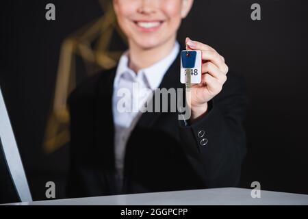 Beschnittene Ansicht von unscharfem und glücklichen Rezeptionisten, der den Zimmerschlüssel hielt Stockfoto