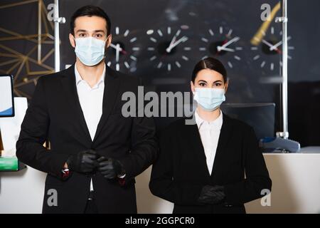 Verwalter in medizinischen Masken und Latexhandschuhen in der Nähe der Rezeption Stockfoto