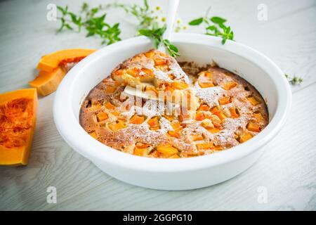 Süßer Kürbiskuchen mit Kürbisscheiben in Keramikform auf einem Holztisch Stockfoto