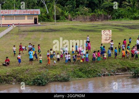 SANTA MARIA DE ANGOTEROS, PERU - 15. JULI 2015: Kinder des Dorfes Santa Maria de Angoteros beobachten ein Boot, das auf einem Fluss Napo ankommt. Stockfoto