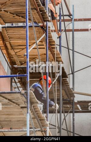 Weißrussland, Bobruisk - 21. August 2020: Industriearbeiter auf Gerüsten in der Nähe eines Gebäudes in der Stadt, Sicherheitsausrüstung. Stockfoto