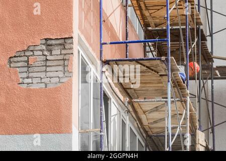 Weißrussland, Bobruisk - 21. August 2020: Ein Industriearbeiter in einem Schutzhelm auf Gerüsten beschäftigt sich mit der Reparatur und dem Wiederaufbau der Fak Stockfoto
