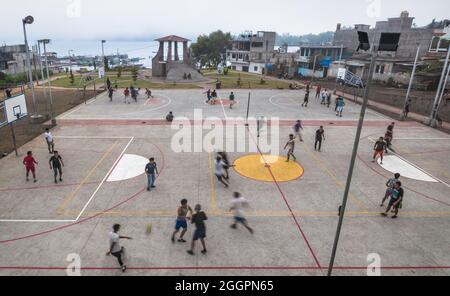 Santiago Atitlan, Guatemala - 29. März 2018: Einheimische Männer spielen Fußball und Basketball auf dem Betonsportplatz am See in Santiago Atitlan Stockfoto