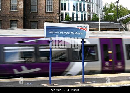 London, England - 2021. August: Unterschreiben Sie auf einem Bahnsteig am Bahnhof Paddington in London. Im Hintergrund ist ein Heathrow Express Zug mit Bewegungsunschärfe Stockfoto