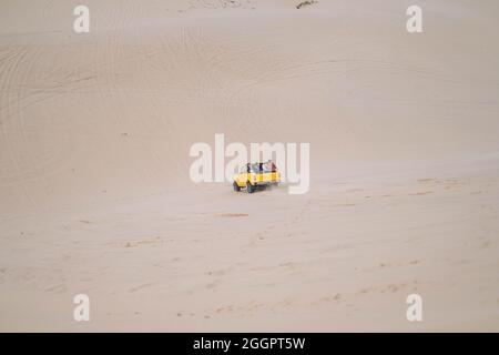 Fantastische Aussicht auf große Autos, die während der Sommerferien auf Sanddünen und Reifenpisten auf Sand fahren. Sanddünen. Touristen in der Wüste. Stockfoto