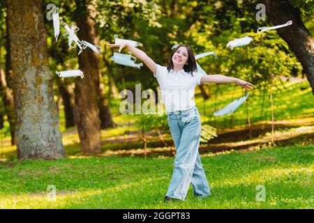 Nahaufnahme einer glücklichen jungen Aktivistin, die im Freien ist und medizinische Masken wirft und gegen Umweltverschmutzung und globale Erwärmung protestiert. Stockfoto