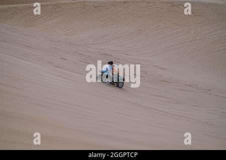 Malerische Aussicht auf ATV fahren auf Sanddünen und Reifenspuren auf Sand an sonnigen Tag während der Sommerferien. Zwei Personen fahren ATV in der weißen Wüste Stockfoto