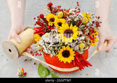 Florist bei der Arbeit: Wie man eine Danksagung Mittelstück mit großen Kürbis und Blumenstrauß. Schritt für Schritt Anleitung. Stockfoto