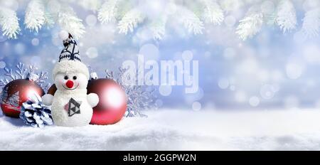 Fröhlicher Schneemann mit Kiefernkegel, Weihnachtsbällen und Schneeflocken auf dem Schnee. Urlaubskonzept. Stockfoto
