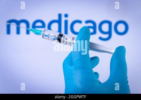 Esp. September 2021. In dieser Abbildung hält eine Hand in medizinischen Handschuhen am 2. September 2021 eine Spritze vor dem Medicago-Logo in Barcelona, Spanien. Medicago ist ein neuer vegetaler Impfstoff gegen Covid-19, der derzeit entwickelt wird. (Foto von Davide Bonaldo/Sipa USA) Quelle: SIPA USA/Alamy Live News Stockfoto