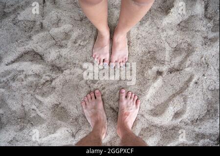 Blick von oben auf Barfußpaar, das im Urlaub am Strand zusammen steht Stockfoto