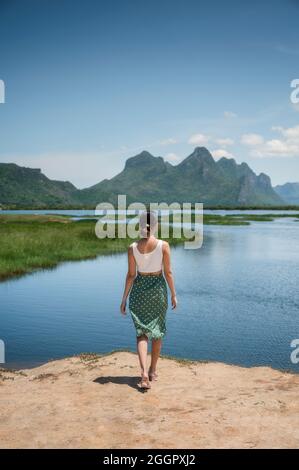 Hinter dem Rücken einer jungen asiatischen Frau, die mit Kalksteinfelsen auf dem Feuchtgebiet im Khao Sam ROI Yot Nationalpark steht Stockfoto