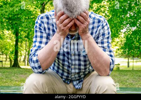 Deprimierter alter Mann, der in einem Park auf der Bank sitzt. Depressionsidee Stockfoto