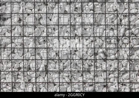 Weiße kleine Steine hinter Metallgitter Dekoration der Straße Außendekor Textur Hintergrund. Stockfoto