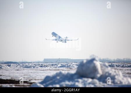 Passagierflugzeug am Flughafen im Winternachmittag. Flugzeug auf Flughafenplattform im Winter. Flugzeug auf Sommerstreifen im Winter Stockfoto