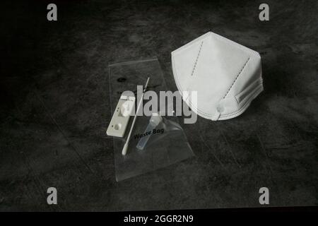 London, UK, 2021.08 Rapid covid Testmaterial mit Ergebnis und Maske auf schwarzem Hintergrund Stockfoto
