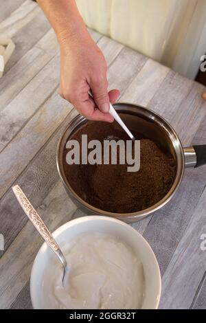 Der Prozess der Herstellung von Schokolade Glasur. Schritt für Schritt. Die Zutaten werden in einem Topf gemischt. Langsam aufwärmen, um sich aufzulösen. Stockfoto