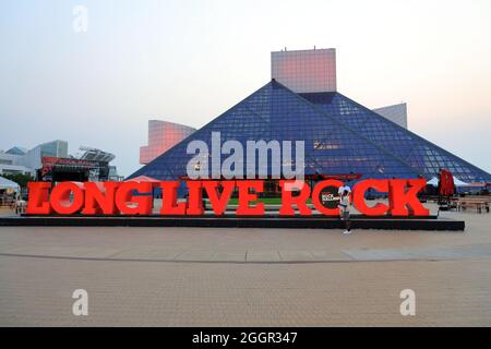 Dämmerungsansicht der Rock and Roll Hall of Fame, entworfen vom Architekten I.M.Pei. Mit Long Live Rock-Schild im Vordergrund.Cleveland.Ohio.USA Stockfoto