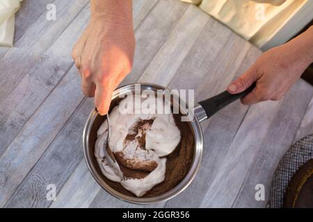 Der Prozess der Herstellung von Schokolade Glasur. Schritt für Schritt. Die Zutaten werden in einem Topf gemischt. Langsam aufwärmen, um sich aufzulösen. Stockfoto