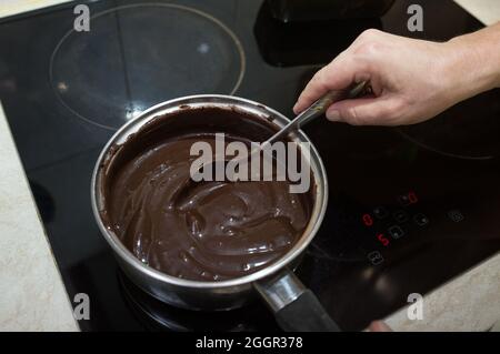 Der Prozess der Herstellung von Schokolade Glasur. Schritt für Schritt. Die Zutaten werden in einem Topf gemischt. Langsam aufwärmen, um sich aufzulösen. Stockfoto