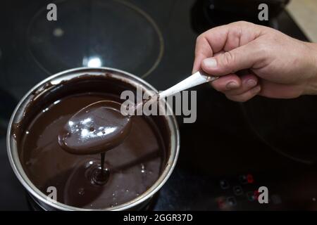 Der Prozess der Herstellung von Schokolade Glasur. Schritt für Schritt. Die Zutaten werden in einem Topf gemischt. Langsam aufwärmen, um sich aufzulösen. Stockfoto