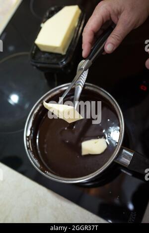 Der Prozess der Herstellung von Schokolade Glasur. Schritt für Schritt. Die Zutaten werden in einem Topf gemischt. Langsam aufwärmen, um sich aufzulösen. Stockfoto