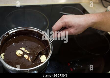 Der Prozess der Herstellung von Schokolade Glasur. Schritt für Schritt. Die Zutaten werden in einem Topf gemischt. Langsam aufwärmen, um sich aufzulösen. Stockfoto