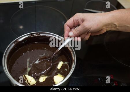 Der Prozess der Herstellung von Schokolade Glasur. Schritt für Schritt. Die Zutaten werden in einem Topf gemischt. Langsam aufwärmen, um sich aufzulösen. Stockfoto