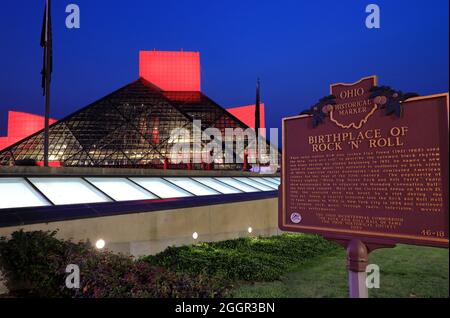 Die Nachtansicht der Roll and Roll Hall of Fame, die vom Architekten I.M.Pei mit dem historischen Marker aus Ohio, Geburtsort des Rock 'n' Roll, im Vordergrund entworfen wurde.Cleveland.Ohio.USA Stockfoto