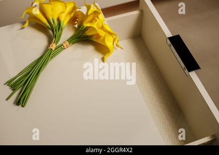 Künstliche Calla Lily Blume auf weißen Holzmöbeln mit Kopierraum Stockfoto