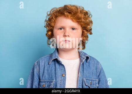 Foto von ruhig fokussierten kleinen Ingwer Foxy Jungen aussehen Kamera tragen Jeans Jacke isoliert blaue Farbe Hintergrund Stockfoto