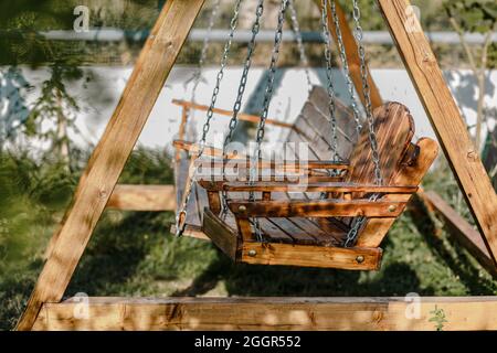 Nahaufnahme einer hölzernen Schaukelbank im Garten während der Sommerferien Stockfoto