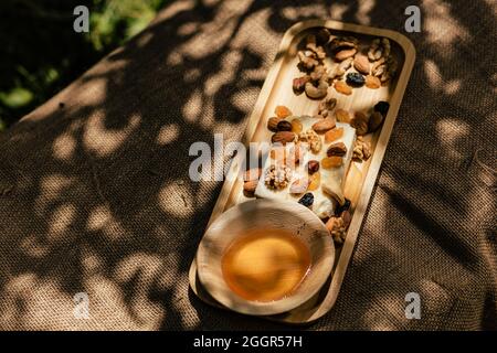 Im Freien Fotoshooting von Käsesortiment mit Honig und Nüssen auf natürlichem Sackleinen-Gewebe im Garten Stockfoto