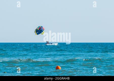 Ukraine, Iron Port - 25. August 2020: Extremsport und spannende Erholung. Eine Gruppe von Menschen mit Touristen auf einem Motorboot mit einem Parashut im blauen Meer Stockfoto