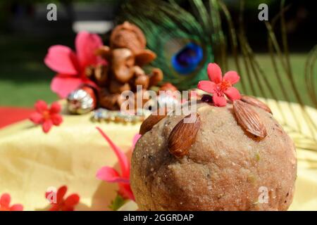 Selektiver Fokus von Laddu süß im Vordergrund und lord Ganesha Idol während Ganesh chaturthifest mit Pfau Feder im Hintergrund angebetet. gan Stockfoto