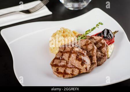 Gegrilltes Rinderfilet-Steak auf einer Keramikplatte mit Butter und Thymian. Filet Mignon Rezept mit Gemüse Stockfoto