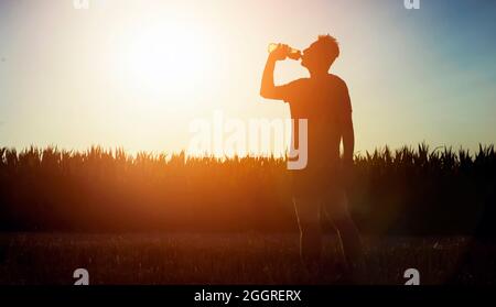 Silhouette eines Athleten mit einer Flasche Wasser. Stockfoto