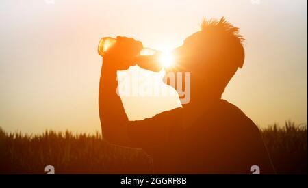 Silhouette eines Athleten mit einer Flasche Wasser. Stockfoto